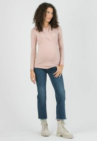 Light pink long-sleeve wrap top with ruching, paired with blue ankle-length jeans and off-white lace-up boots with chunky soles.