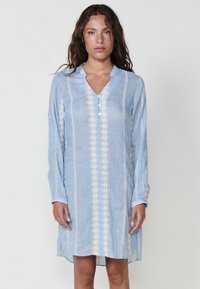 Helles blaues Leinenkleid mit V-Ausschnitt, langen Ärmeln und weißen bestickten Akzenten an der Vorderseite und den Ärmeln, mit Seitenschlitzen.