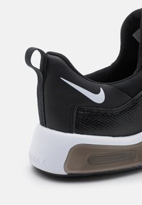 Musta lenkkari, jossa on verkkomateriaali, valkoinen Nike -logo, pehmustettu kaula ja läpinäkyvä ilmatyyny yksikkö tekstuurilla varustetussa pohjassa.