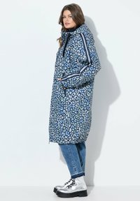 Prošívaný, po kolena dlouhý puffr kabát v modré barvě s leopardím vzorem. Obsahuje kapuci, postranní kapsy a kontrastní boční pruhy.