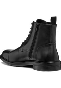 Botín negro de cuero hasta el tobillo con punta redonda, cremallera lateral y parte superior con cordones. Cuenta con una suela de goma texturizada para agarre y durabilidad.