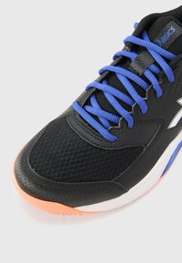 Black athletic shoe with breathable mesh and synthetic material. Features blue laces, a rubber sole with orange accents, and white midsole.