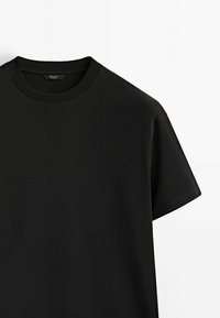 T-shirt noir à manches courtes avec col rond côtelé sur fond blanc.