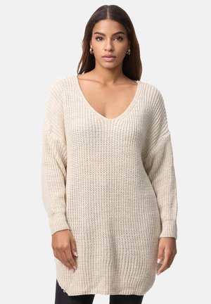 Crèmekleurige gebreide trui met een diepe V-hals, verlaagde schouders en ribgebreide manches. Lange, losvallende snit met een gestructureerd patroon.