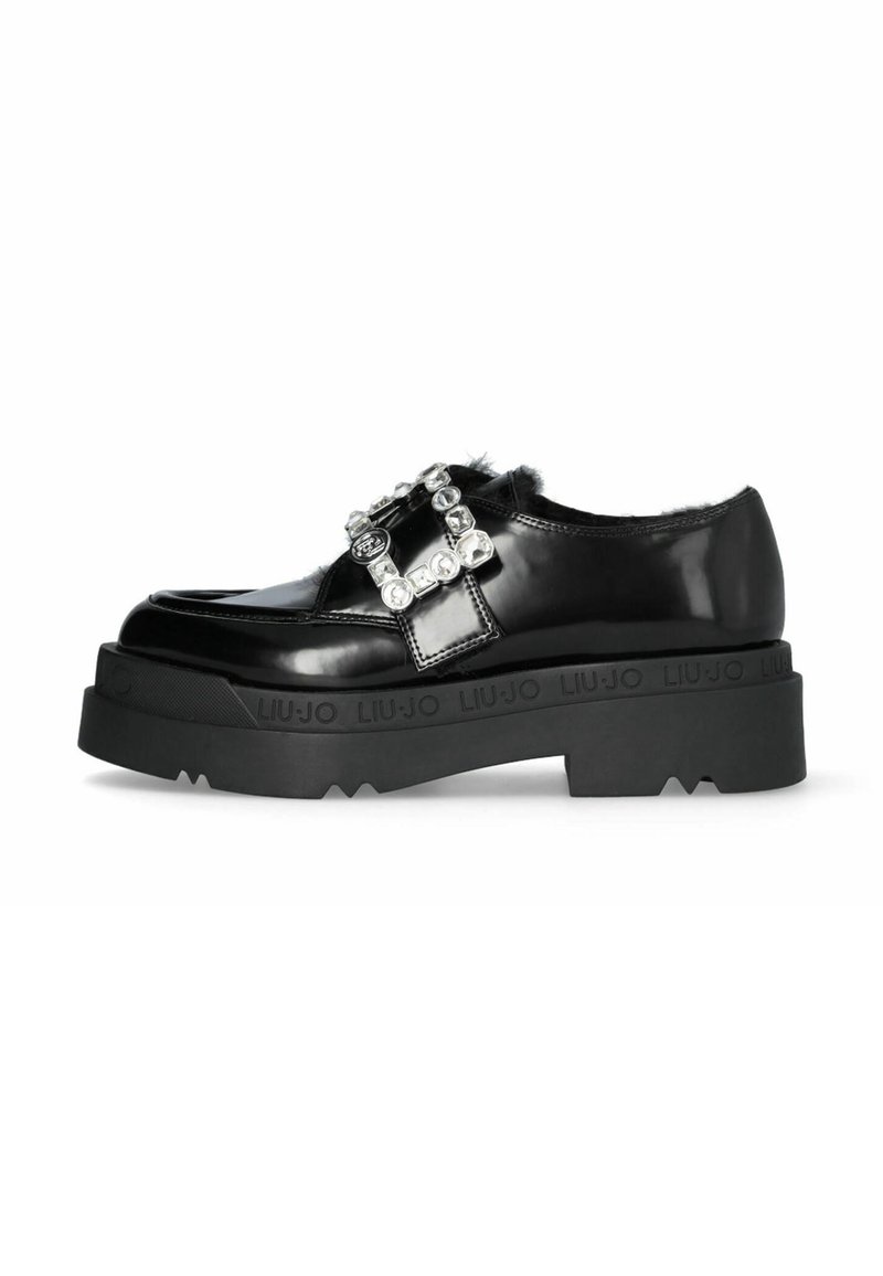 Black patent leather shoe with a chunky black platform and decorative rhinestone buckle. Features fur accents and textured rubber sole.