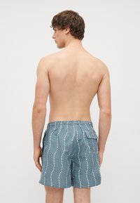 Blue swim shorts made of lightweight material featuring a white wavy pattern and an elastic waistband with a back pocket.