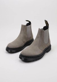 Harmaat mokka Chelsea -saappaat, joissa on joustavat sivupaneelit, mustat kumipohjat ja vetolenkit helppoa pukemista varten. Teksturoitu pinta ja pyöreä kärkipohja.