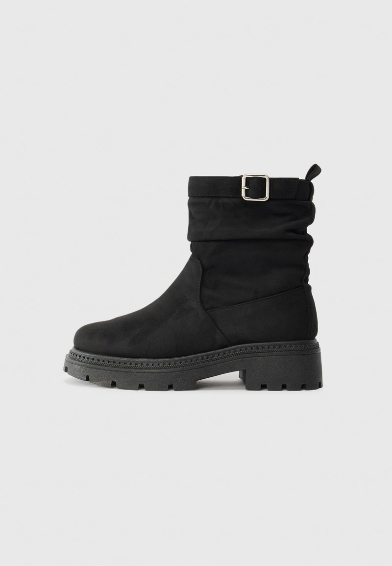 Schwarze Ankelschuhe mit einem lässigen Design, aus weichem Material, mit einer seitlichen Schnalle und dicker, profilierten Sohle für besseren Halt.