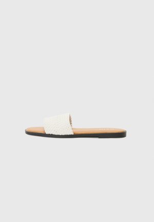 Woven white slide sandal with a textured strap, brown insole, and a thin black sole. Casual design suitable for warm weather.