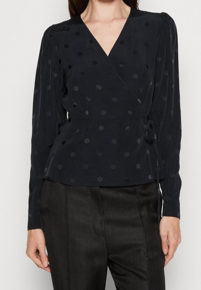 Námornícky blouse s poisťkovým vzorem, s dlouhými rukávy a peplum pasem. Vyrobeno z lehkého materiálu s hladkou texturou.