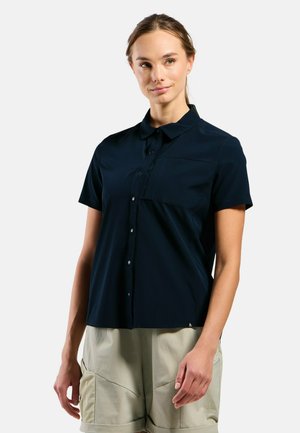 Navy short-sleeve shirt with button closure, chest pocket, and smooth texture. Features a curved hem and subtle branding on the lower side.