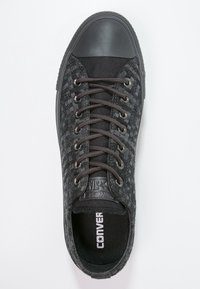 Černé plátěné tenisky se strukturovaným vzorem, gumovým krytem špičky a tmavými tkaničkami. Obsahují logo na jazyku a polstrovanou stélku.