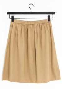 Gonna khaki, a metà coscia, realizzata in tessuto morbido, con vita elastica, vestibilità ampia e una texture sottile su tutta la superficie. Appesa a una gruccia nera.