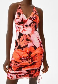 Mini abito a halter floreale con colori vivaci di rosa, rosso e nero, con un design arricciato sul lato e legature regolabili all'orlo.