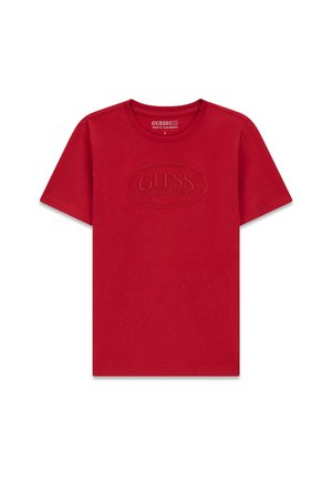T-shirt rouge à manches courtes avec col rond et logo embossé "GUESS Los Angeles" centré sur la poitrine.