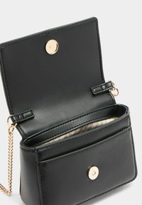 Piccola borsa a tracolla di pelle nera con chiusura a scatto dorata. Presenta una tracolla a catena e una fodera interna a righe. Design rettangolare compatto.