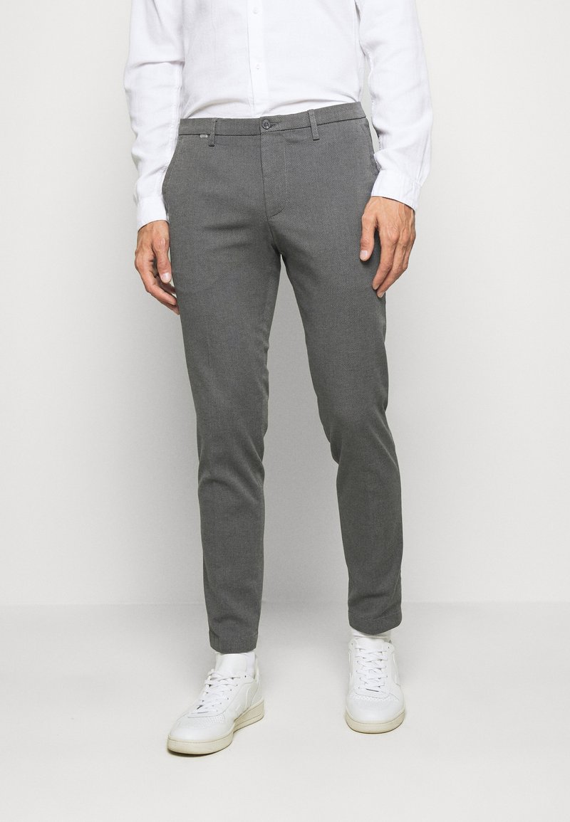 Graue maßgeschneiderte Hose aus strukturiertem Stoff, schmaler Schnitt und mit Vorderasstaschen, kombiniert mit weißen Sneakers.