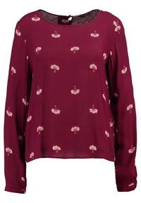 Blouse bordeaux à manches longues avec imprimé floral blanc, encolure ronde et fermeture à œillet au dos. Tissu léger et texturé.