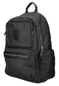 Sac à dos noir en tissu texturé, avec une poche zippée à l'avant, un patch logo et des accents en cuir, doté d'une poignée supérieure rembourrée et de bretelles ajustables.