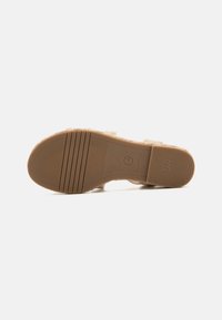 Tan slip-on sandal with textured upper, rubber sole, and horizontal grooves for grip. Marked with brand logo on the footbed and sole.