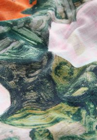 Farebná tkanina s abstraktnými vzormi v zelenej, ružovej a oranžovej farbe. Textúra vyzerá ľahká a mierne zvinutá.