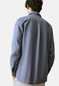 Camicia grigia a maniche lunghe in cotone con colletto button-down, polsini a un pulsante e orlo arrotondato, vista dal retro.