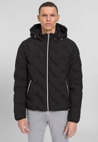 Schwarze gesteppte Pufferjacke mit Kapuze, vorderem Reißverschluss und seitlichen Reißverschlusstaschen. Mit elastischen Bündchen und einer glatten, glänzenden Textur.