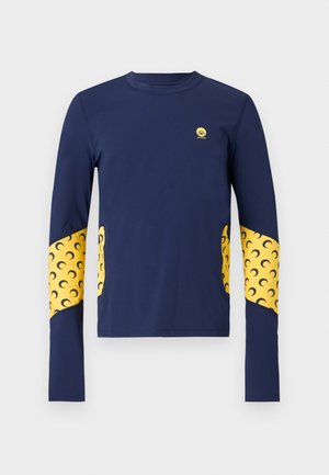 Chemise bleu marine à manches longues avec des panneaux jaunes à motif croissant sur les manches et les côtés, avec un petit logo circulaire jaune sur la poitrine.
