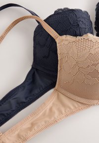 Deux soutiens-gorge : un bleu marine avec une superposition de dentelle et un tissu en résille, un nude avec un design en dentelle florale. Les deux comportent des bretelles réglables et des bonnets sans couture.