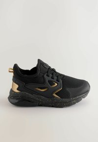 Chaussure de sport noire avec une tige en mesh, accents dorés, semelle noire mouchetée, structure de soutien et une languette à l'arrière pour unEnfilement facile.