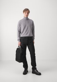 Pulover gri cu guler înalt, blugi negri, geantă neagră și pantofi negri. Textură netedă, design simplu, fără motive sau accente vizibile.