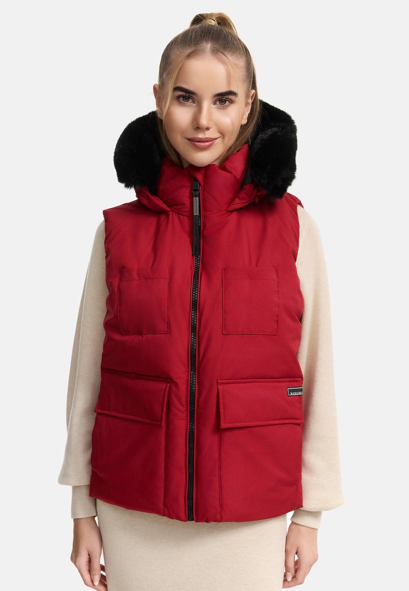 Gilet imbottito rosso con cappuccio in finta pelliccia nera staccabile, molteplici tasche frontali e una zip a doppio cursore; texture liscia e design imbottito.