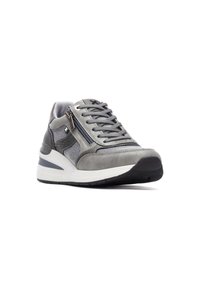 Zapatilla deportiva gris que presenta una combinación de gamuza suave y tela texturizada, con cordones en la parte delantera, cremallera lateral y una suela gruesa blanca.
