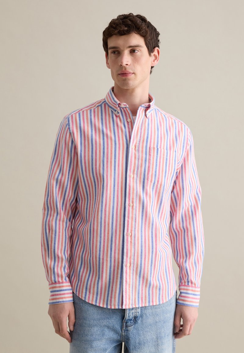 Camisa de botones con rayas verticales en rojo, azul y blanco, con un cuello y un bolsillo en el pecho. Fabricada en un tejido ligero.