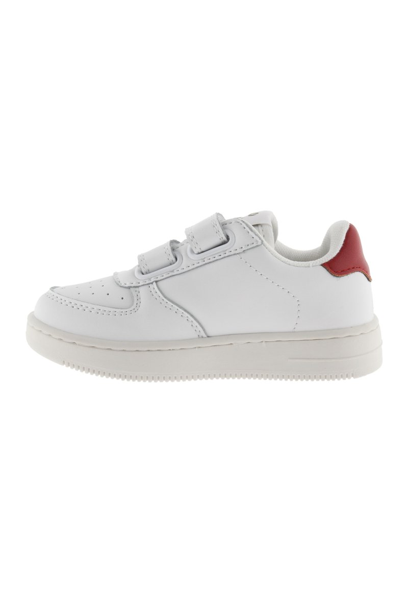 Baskets en cuir blanc avec un accent rouge sur le talon, dotées de deux bandes Velcro, d'un bout arrondi et d'une semelle en caoutchouc texturée.