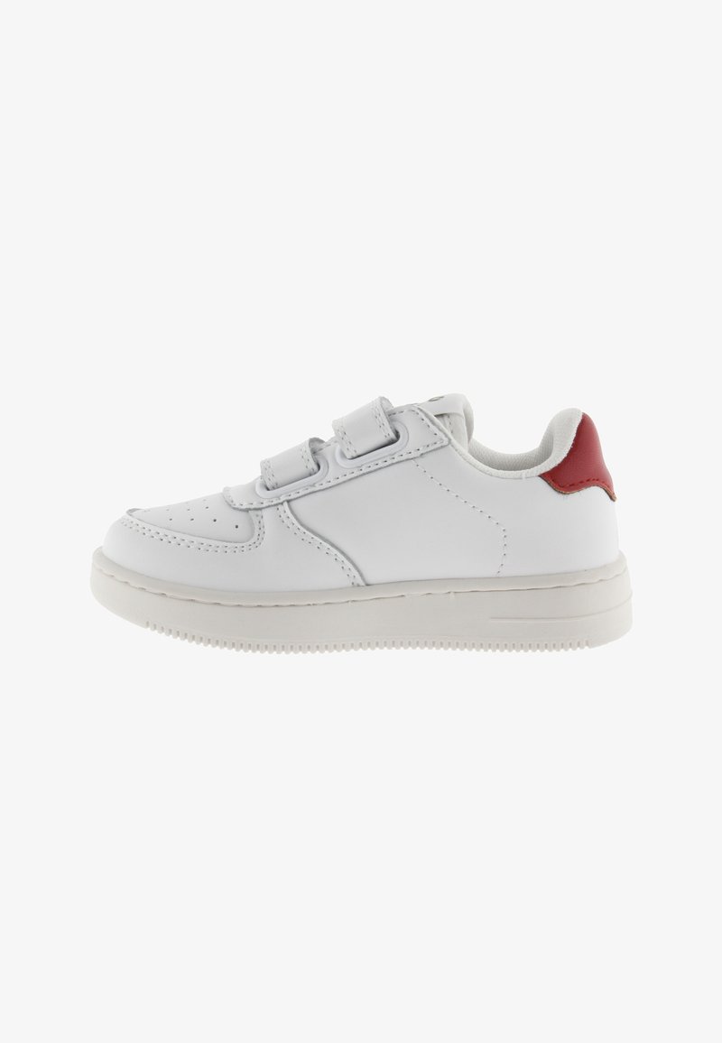 Baskets en cuir blanc avec un accent rouge sur le talon, dotées de deux bandes Velcro, d'un bout arrondi et d'une semelle en caoutchouc texturée.