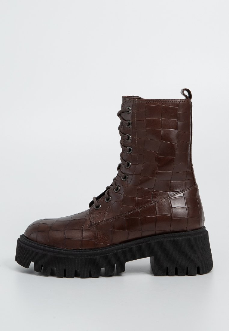 Braune Leder-Schnürstiefelette mit strukturiertem Krokodil-Muster, schwarzer, klobiger Sohle und Metallösen für die Schnürsenkel.