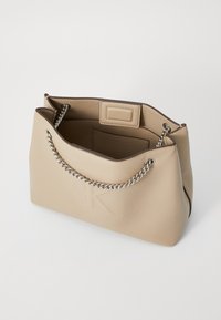 Borsa tote in ecopelle beige con manici in catena argentata, logo impresso sul davanti e una texture morbida e liscia. Design con apertura superiore.