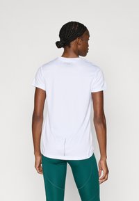 Weißes Sport-T-Shirt mit kurzen Ärmeln und rundem Ausschnitt, mit einem dezenten Logo auf der Rückseite und einem kleinen Belüftungsschlitz am Saum.