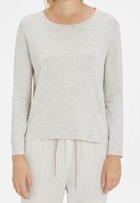 Pullover grigio chiaro a maniche lunghe, leggermente morbido, con scollatura rotonda, texture del tessuto morbida, cuciture minime, abbinato a pantaloni di colore chiaro.