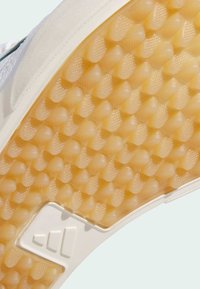 Gummisula med ett texturerat honungsbikake-mönster i ljust brunt. Har en vit kant och ett formsprutat varumärkeslogo i hörnet.