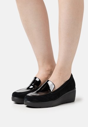 Black wedge shoes made of suede with glossy patent leather accents. Features a rounded toe and slip-on design.