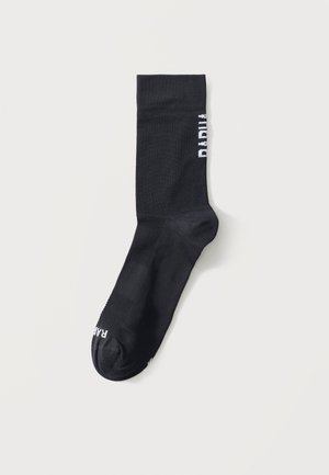 Fekete közép-szárú zokni texturált talprészel, fehér részleges felirattal az oldalán és a lábujjrészén, fehér háttéren elhelyezve.