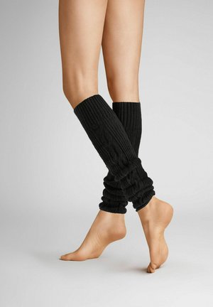 Schwarze gestrickte Beinwärmer mit geripptem Muster und gerafftem Design, die vom Wadenmittelpunkt bis zum Knöchel reichen und über barfuß getragen werden.