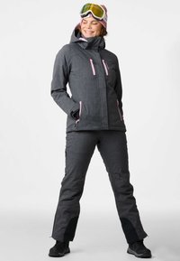 Graue Skijacke mit pinken Reißverschlüssen, kombiniert mit passenden grauen Hosen. Verfügt über eine Kapuze, Taschen und schwarze Akzente an den Hosenbeinen.