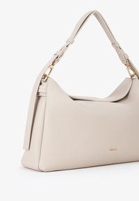 Borsa a mano in pelle beige con forma strutturata, tracolla removibile e dettagli in metallo dorato. Superficie morbida e testurizzata con un branding sottile.