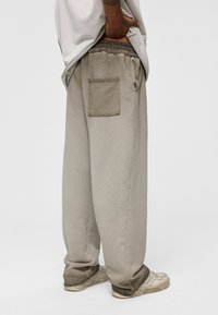 Beige katoenen sweatpants met een comfortabele pasvorm, voorzien van een elastische tailleband met trekkoord en een achterzak. Licht taps toelopend bij de enkels.