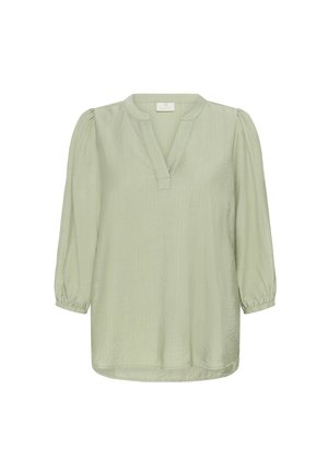 Blouse vert clair à manches trois quarts, avec un col en V et des poignets froncés. Tissu texturé, coupe ample et ourlet arrondi avec des détails de couture.