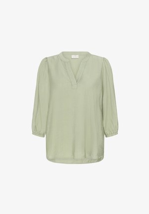 Heled rohelise tooni, kolmeveerandvarrukatega bluus V-kaelusega ja kogutud mansettidega. Tekstuuriga kangas, lõdva lõikega ja ümaral hemil on õmblustäht.