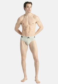 Mäns ljusgrå kalsonger i ett mjukt, stretchigt tyg, med en svart märkeslinning med tre ränder design.